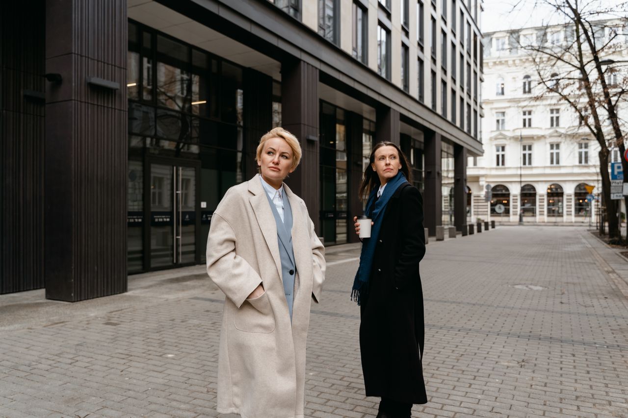 services-03 Businesswomen in formal attire walking outside a modern office building, conveying professionalism.