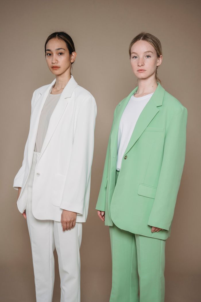 services-02 Two women in stylish suits posing against a neutral background, highlighting modern fashion.